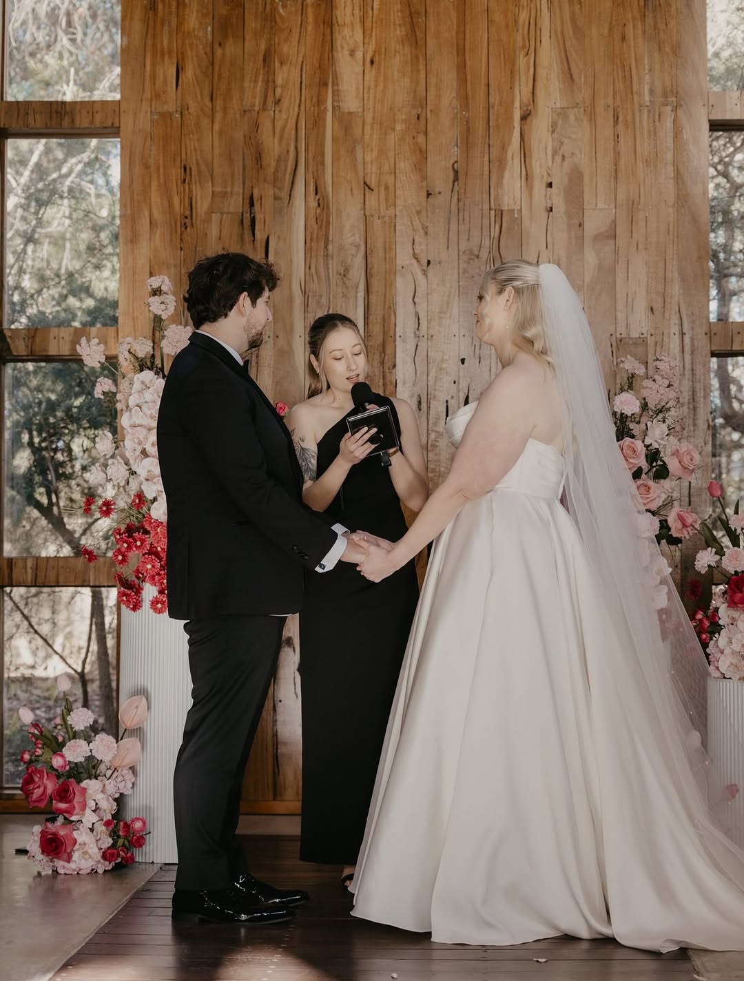 Photo of Love Stories by Kira officiating a wedding with a floral background